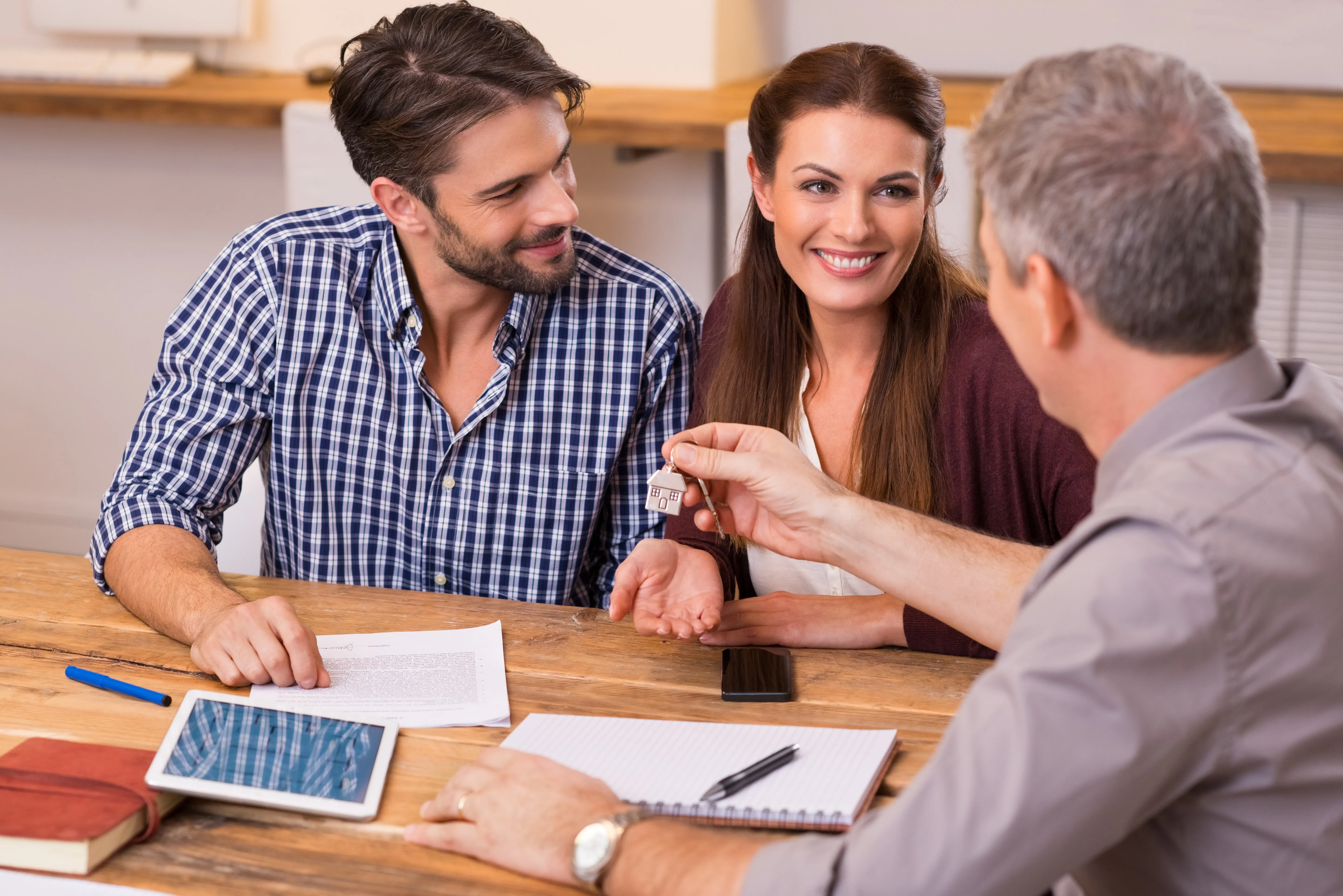 Loan officer handing house keys to a happy Florida couple at closing